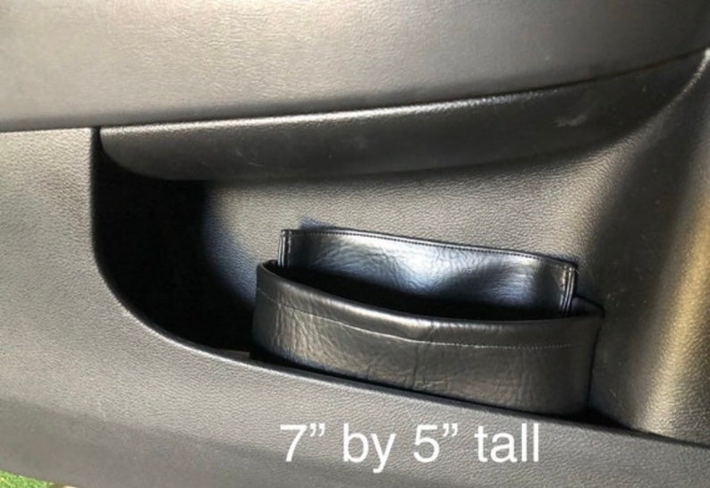 May include: Black leather car door organizer with a 7" by 5" tall measurement.