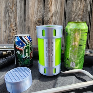 Puede incluir: Un enfriador de latas verde lima y plateado con el texto "TERI" y un posavasos azul claro se muestran junto a dos latas de bebidas. Una lata es azul y blanca con un diseño de montaña, y la otra es verde.