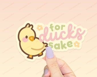 May include: A yellow cartoon duck with pink cheeks and a brown beak. The duck is holding a sign that says "for duck's sake" in pink and green letters with white flowers.