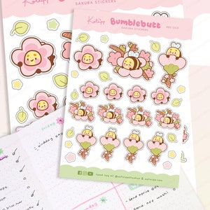 May include: A sheet of stickers featuring a cute cartoon bee with pink flowers and green leaves. The stickers are designed for use in a planner or journal. The text on the sheet reads "Kotipp Bumblebutt Sakura Stickers BBS 003".