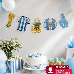 May include: A party banner featuring cutouts of a gold trophy, a blue and white striped soccer jersey, the AFA crest, a soccer ball, and a blue foam finger. The banner hangs above a white cake, blue and white striped popcorn boxes, and balloons.