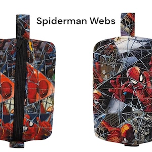 May include: Two rectangular pouches with a black zipper and a loop at the top. The pouches are covered in a comic book print featuring Spider-Man and his webs. The text "Spiderman Webs" is above the pouches.
