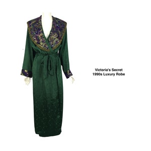 May include: A green Victoria's Secret 1990s luxury robe. The robe features a shawl collar with gold, purple, and green embroidery. The long-sleeved robe has a matching tie belt and cuffs with purple accents.