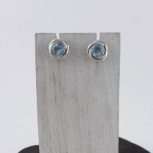 May include: A pair of silver stud earrings with light blue round gemstones.