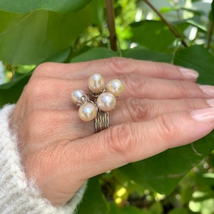 Op de afbeelding: Een zilveren ring met een cluster van vijf crèmekleurige parels.