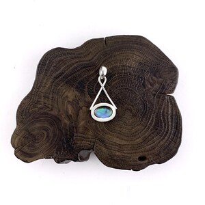 May include: A silver pendant with a blue and green abalone shell inlay, set in a triangular frame.