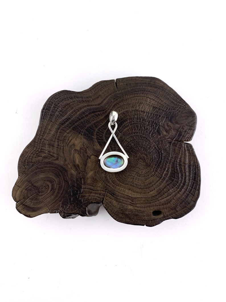 May include: A silver pendant with a blue and green abalone shell inlay, set in a triangular frame.