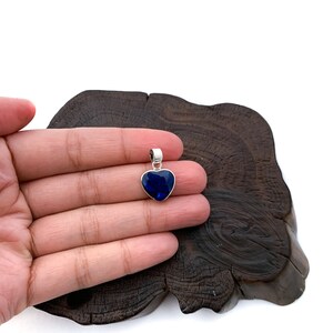 May include: A silver heart-shaped pendant with a dark blue gemstone.