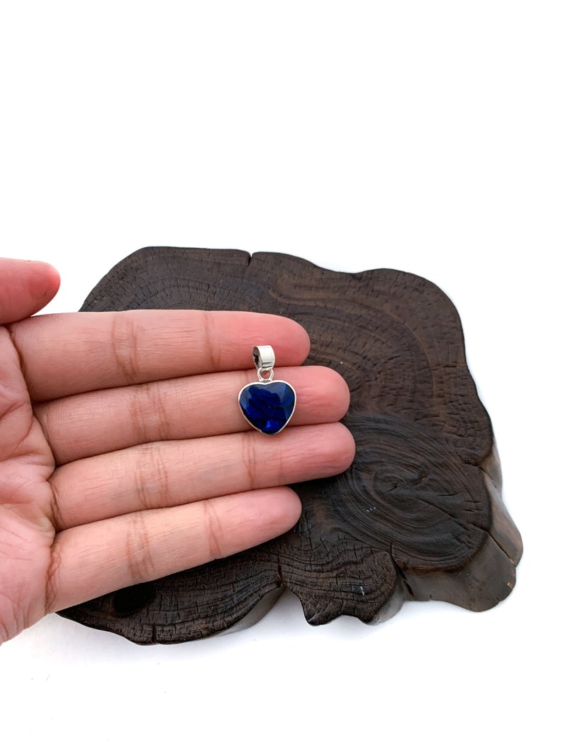 May include: A silver heart-shaped pendant with a dark blue gemstone.