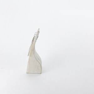 May include: Silver dangle earrings with a simple design, displayed on a white wooden stand.