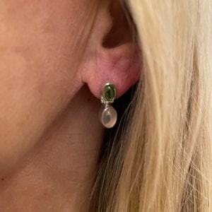 May include: Silver earrings with a green oval gemstone and a white oval gemstone.