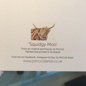 Puede incluir: Una tarjeta de felicitaci&oacute;n con una pintura de acuarela de una vaca de las Tierras Altas, con pelo largo y marr&oacute;n y cuernos. El texto dice "Squidgy Moo" y menciona a la artista, Jo McColl, y que fue pintada e impresa en Escocia.