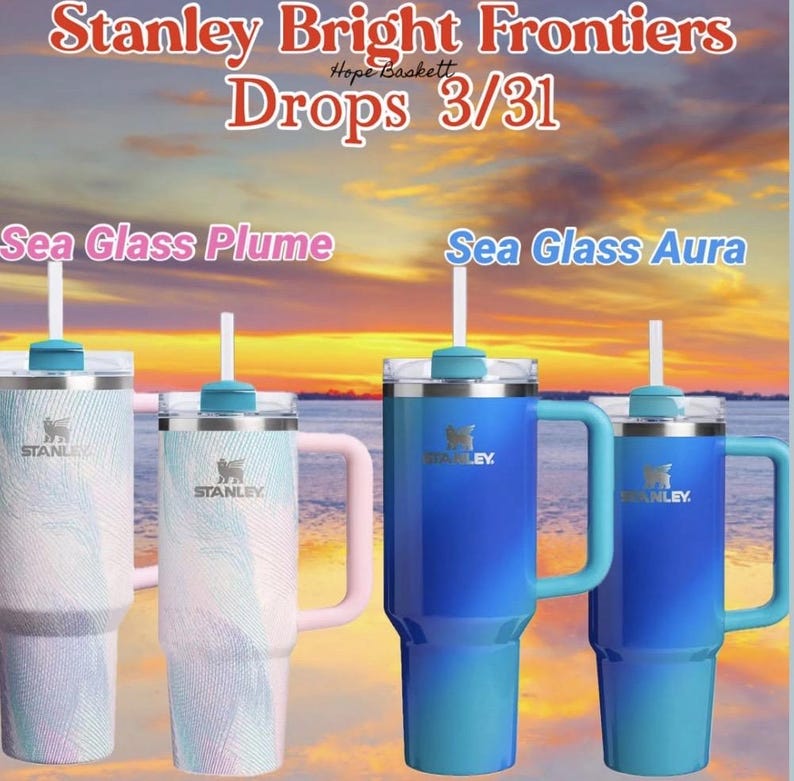 May include: Four Stanley tumblers with handles and straws are displayed. Two are blue, one is white with a pink handle, and one is white with a blue handle. The text "Stanley Bright Frontiers Drops 3/31" is at the top.
