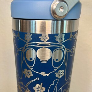 May include: A blue stainless steel travel mug with a blue lid and a silver handle. The mug has a pattern of Stitch characters and flowers.