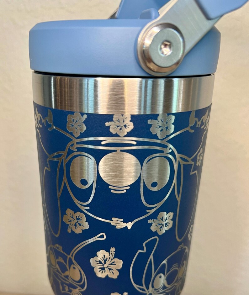 May include: A blue stainless steel travel mug with a blue lid and a silver handle. The mug has a pattern of Stitch characters and flowers.