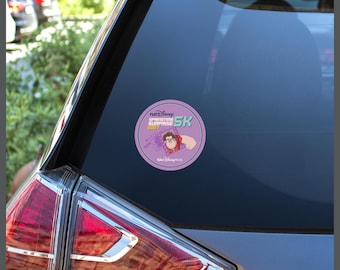 May include: A circular sticker adhered to a car window featuring the text runDisney Springtime Surprise 2021 and Walt Disney World. The design includes a graphic of the character Wreck-It Ralph on a light purple background with a dark purple border.
