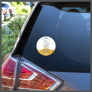 May include: A white and gold round sticker with a blue and white illustration of Cinderella's castle. The text "runDisney Virtual Challenge" and "Happily Ever After 2023" is on the sticker.