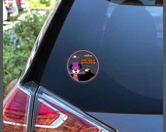 May include: A circular sticker adhered to a car window featuring a graphic of a cartoon mouse dressed as a vampire in a purple top hat and cape. The text reads runDisney Virtual SPOOKTACULAR 20 CHALLENGE 26 with a small white moon above.