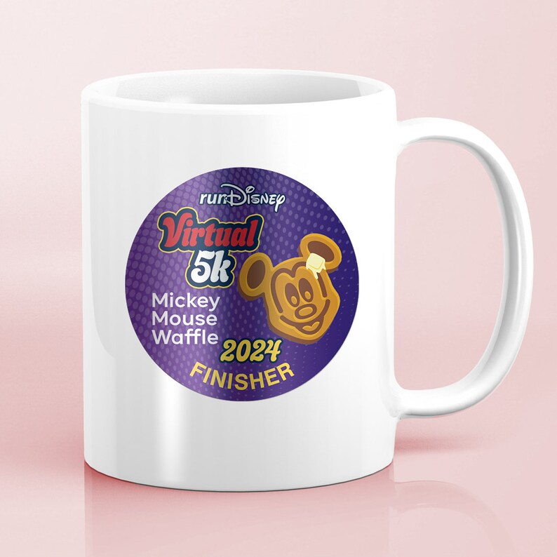 May include: White ceramic mug featuring a purple and gold graphic for the Virtual 5K Mickey Mouse Waffle 2024 Finisher runDisney event. The graphic includes a waffle shaped like Mickey Mouse with a pat of butter.