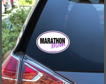 May include: White oval car sticker with a purple border. The sticker says "Marathon Mom" in black and purple text.