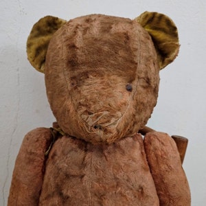 Peut inclure: Un ours en peluche vintage brun avec des oreilles en feutre jaune. L'ours est usé et il manque quelques morceaux de fourrure.