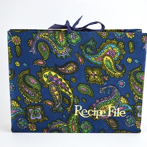 May include: A rectangular recipe file with a navy blue paisley pattern. The file is tied with a navy blue ribbon. The words "Recipe File" are printed in gold script on the front.