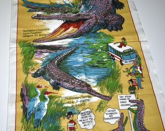 May include: A vintage, rectangular, yellow and white tea towel featuring illustrations of crocodiles in a natural habitat. The towel includes text that reads "CROCODILE AUSTRALIA" and "DESIGNED IN AUSTRALIA".