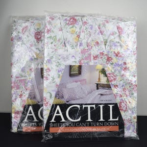 May include: Two packaged Actil sheet sets. The sheets have a white background with a floral pattern in pink, purple, and yellow. The packaging includes the text "ACTIL SHEETS YOU CAN'T TURN DOWN". The pillowcase size is 48cm x 73cm.
