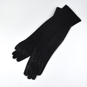 May include: A pair of long black gloves featuring a smooth finish and visible stitched detailing along the fingers and back of the hand. The gloves extend past the wrist, showcasing a classic design with clean lines and a uniform dark color.