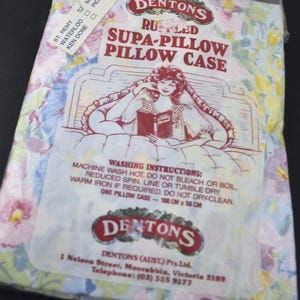 May include: A pillowcase in a plastic bag with a floral pattern in pink, blue, and yellow. The packaging features the text "DENTONS RUSTLED SUPA-PILLOW PILLOW CASE" and washing instructions. The pillowcase measures 39.37 inches x 22.83 inches.