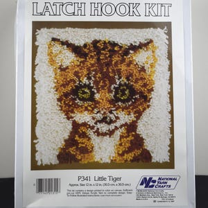 May include: Latch hook kit featuring a colorful tiger design. The kit includes a printed canvas, pre-cut acrylic yarn, and instructions. The finished size is approximately 12 in. x 12 in.