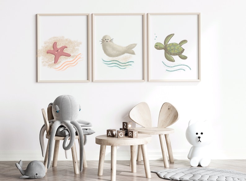 Three separate framed illustrations of a sea turtle, starfish and a seal hanging on the wall on a child’s playroom with toys