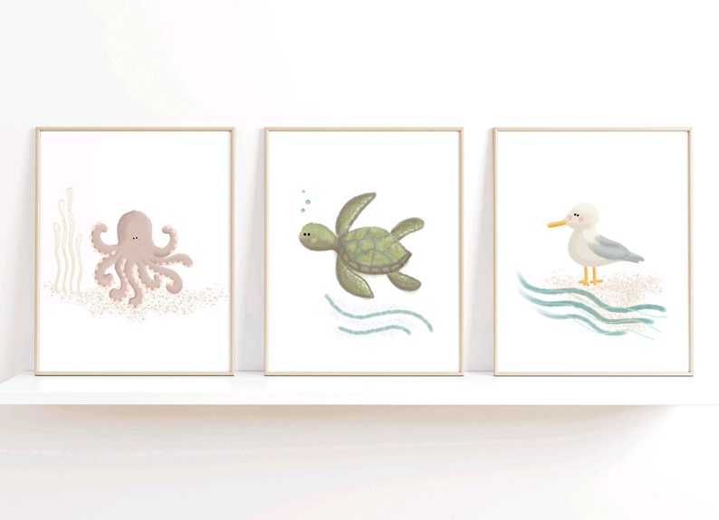 Illustration of sea turtle, octopus and sea gull in 3 wood frames sitting on a white shelf