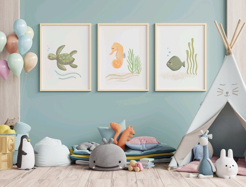 Three separate framed illustrations of a sea turtle, sea horse and a fish hanging on the wall on a child’s playroom with toys
