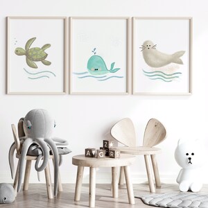 Three separate framed illustrations of a sea turtle, whale and a seal hanging on the wall on a child’s playroom