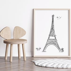 Black and white Eiffel Tower line drawing in frame in neutral nursery with kid’s chair