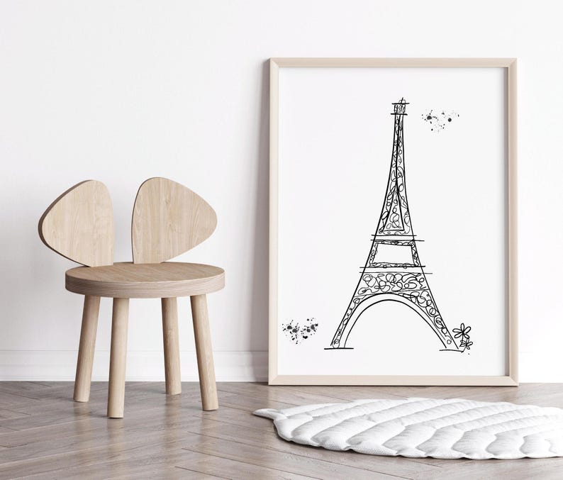 Black and white Eiffel Tower line drawing in frame in neutral nursery with kid’s chair