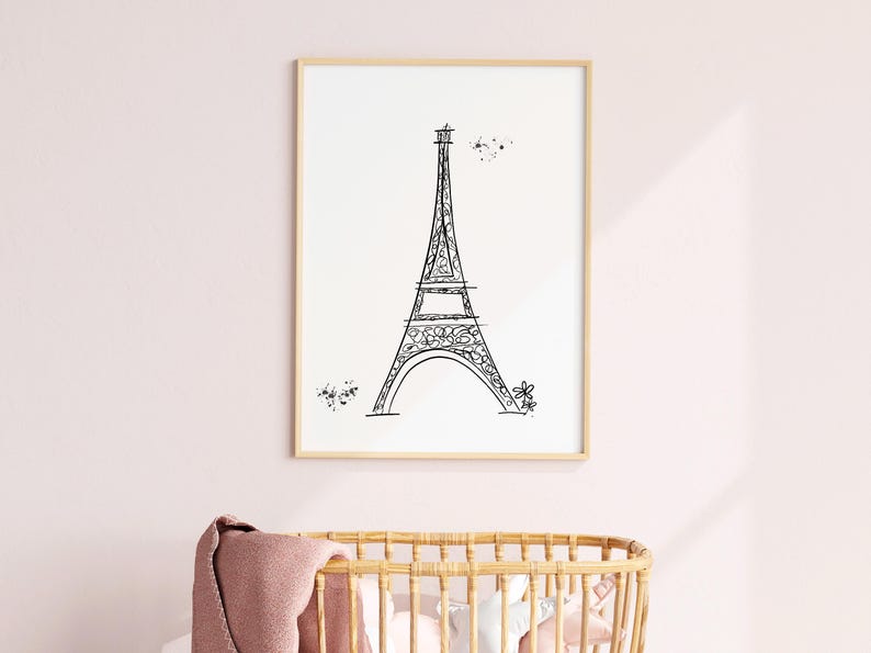 Black and white Eiffel Tower line drawing in frame in pink nursery above a crib