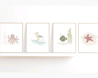 以下が含まれることがあります： 海の生き物のイラストが描かれた額装されたプリントが4枚。プリントには、ピンクのタコ、灰色のカモメ、緑の魚、ピンクのヒトデが描かれています。各プリントは白い背景に薄い青色の波模様が描かれています。