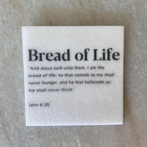 May include: White card with black text that reads "Bread of Life" and a quote from the Bible, John 6:35. The quote reads "And Jesus said unto them, I am the bread of life: he that cometh to me shall never hunger, and he that believeth on me shall never thirst."