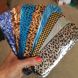 May include: A collection of eight different patterned vinyl sheets. The sheets are arranged in a fan shape and feature a variety of colors and designs, including blue, brown, gold, and black.