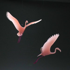 Może przedstawiać: Dwie różowe dekoracje flamingów wiszące z sufitu. Flamingi są wykonane z przezroczystego materiału i mają delikatny, fantazyjny wygląd.