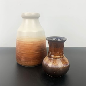 May include: Two ceramic vases, one white with brown stripes and one brown with a glossy finish.