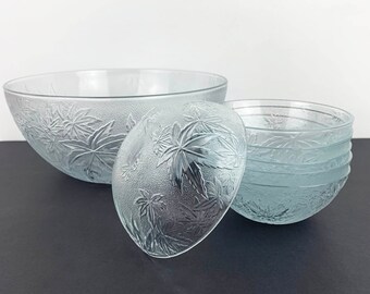 May include: A set of clear glass bowls with a leaf pattern. The set includes a large bowl and four smaller bowls.