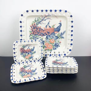 Puede incluir: Un juego de platos de cerámica blanca con un diseño de celosía azul y blanco y un diseño de pavo real. Los platos son de diferentes tamaños y están apilados uno encima del otro.