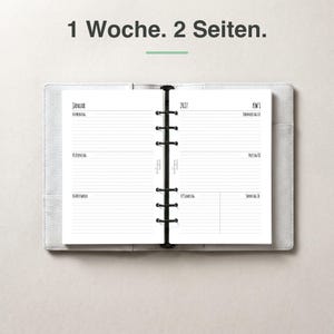 Könnte beinhalten: Ein weißer Ringbuch-Planer, der eine Wochenansicht zeigt, mit dem Text 1 Woche. 2 Seiten. oben. Die Seiten enthalten das Jahr 2027, den Monat Januar und die Wochentage auf Deutsch, strukturiert mit horizontalen Linien für tägliche Notizen.