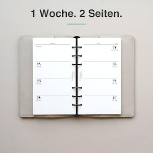 Könnte beinhalten: Ein hellgrauer Ringbuchplaner, der auf eine Wochenansicht mit weißen Seiten aufgeschlagen ist. Der Text 1 Woche. 2 Seiten. steht oben. Der Planer zeigt die Daten vom 4. bis 10. Januar 2027 mit einer schwarzen Sechs-Ring-Metallmechanik.