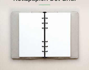 May include: An open ring-bound planner with white dot grid paper and a black metal six-ring mechanism, set inside a light gray cover. The text Notizpapier. Dot Grid. is displayed above the planner in a dark gray sans-serif font.