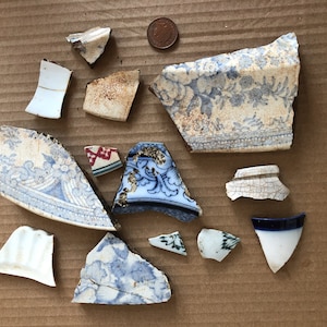 Puede incluir: Una colección de piezas de porcelana azul y blanca rotas con motivos florales. Las piezas están dispuestas sobre una superficie de cartón marrón.