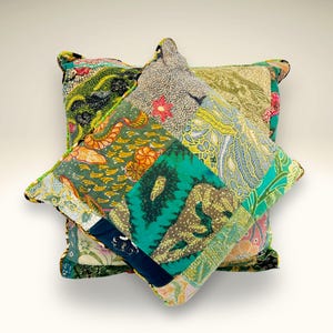May include: Two patchwork pillow covers with a green, blue, yellow, and orange floral pattern. The pillow covers are made from different fabrics and sewn together to create a unique design.